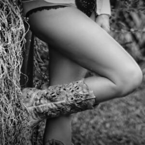 Country Dreams by Zoe McKay. Image shows a female leg bent at the knee with bottom of boot resting against a haystack.
